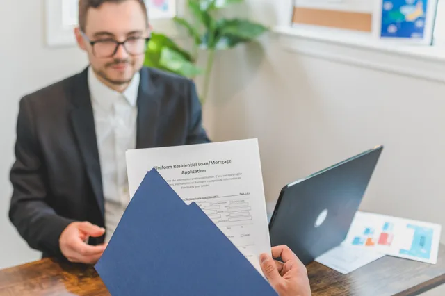Mortgage broker and client discussing loan application with documents on table. Digital lending problems: a guide to tracing account issues